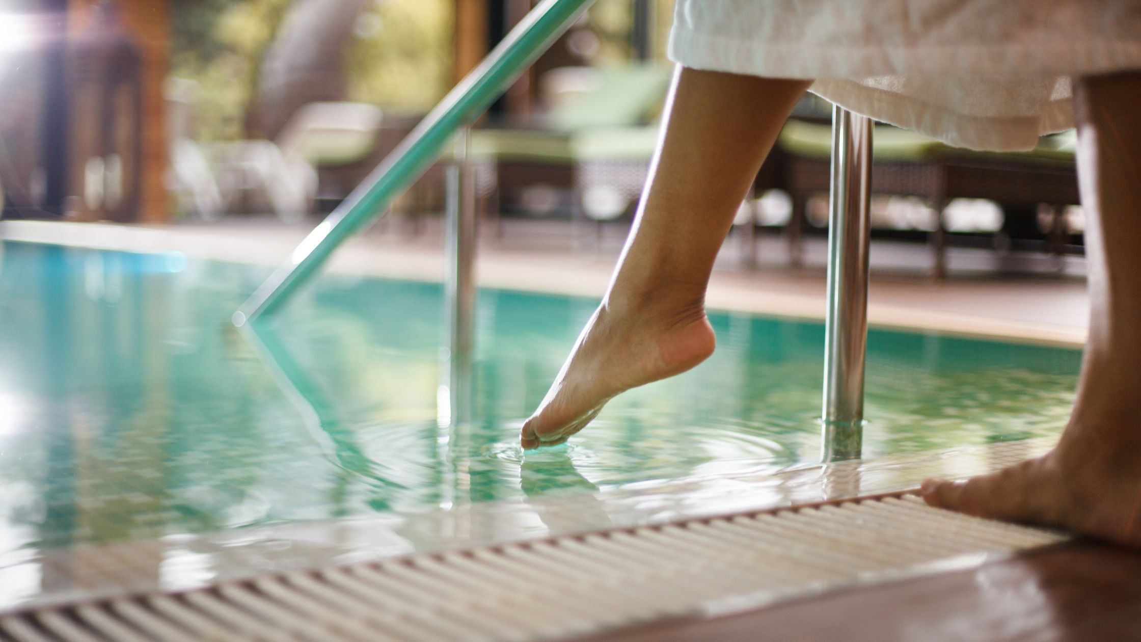 Person dipping their toes into a swimming pool while one foot stays on the deck, representing how people ease into change in the workplace