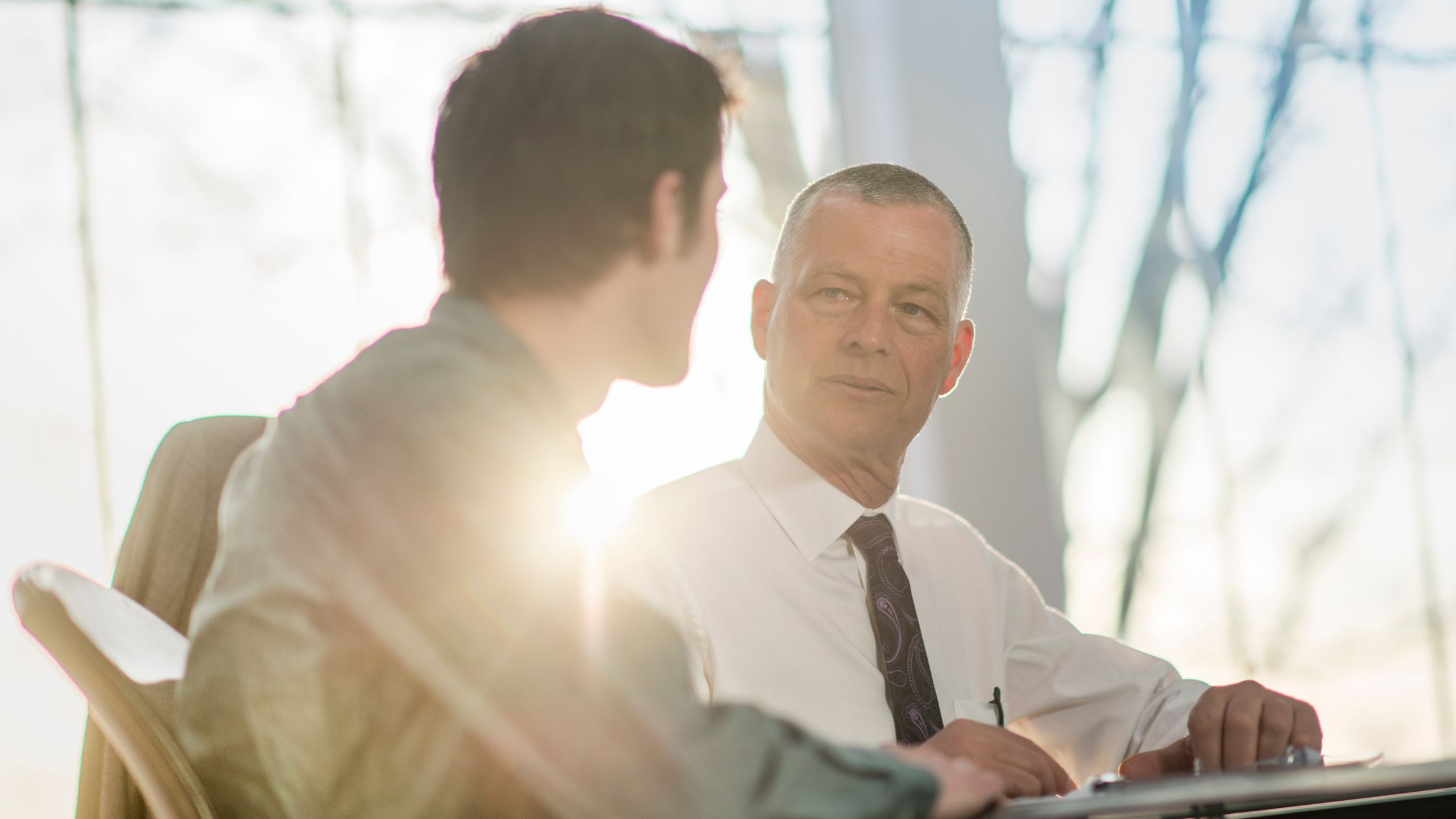 An experienced leader teaching and mentoring a colleague at his desk
